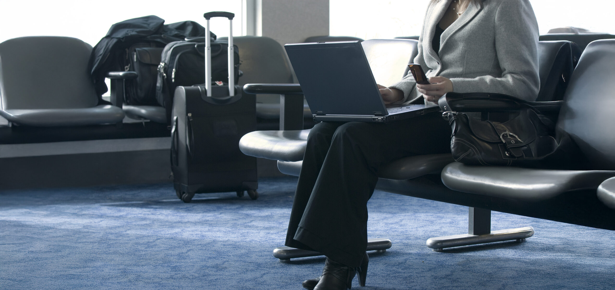 Businesswoman waiting for an airplane working on her laptop and cellphone.